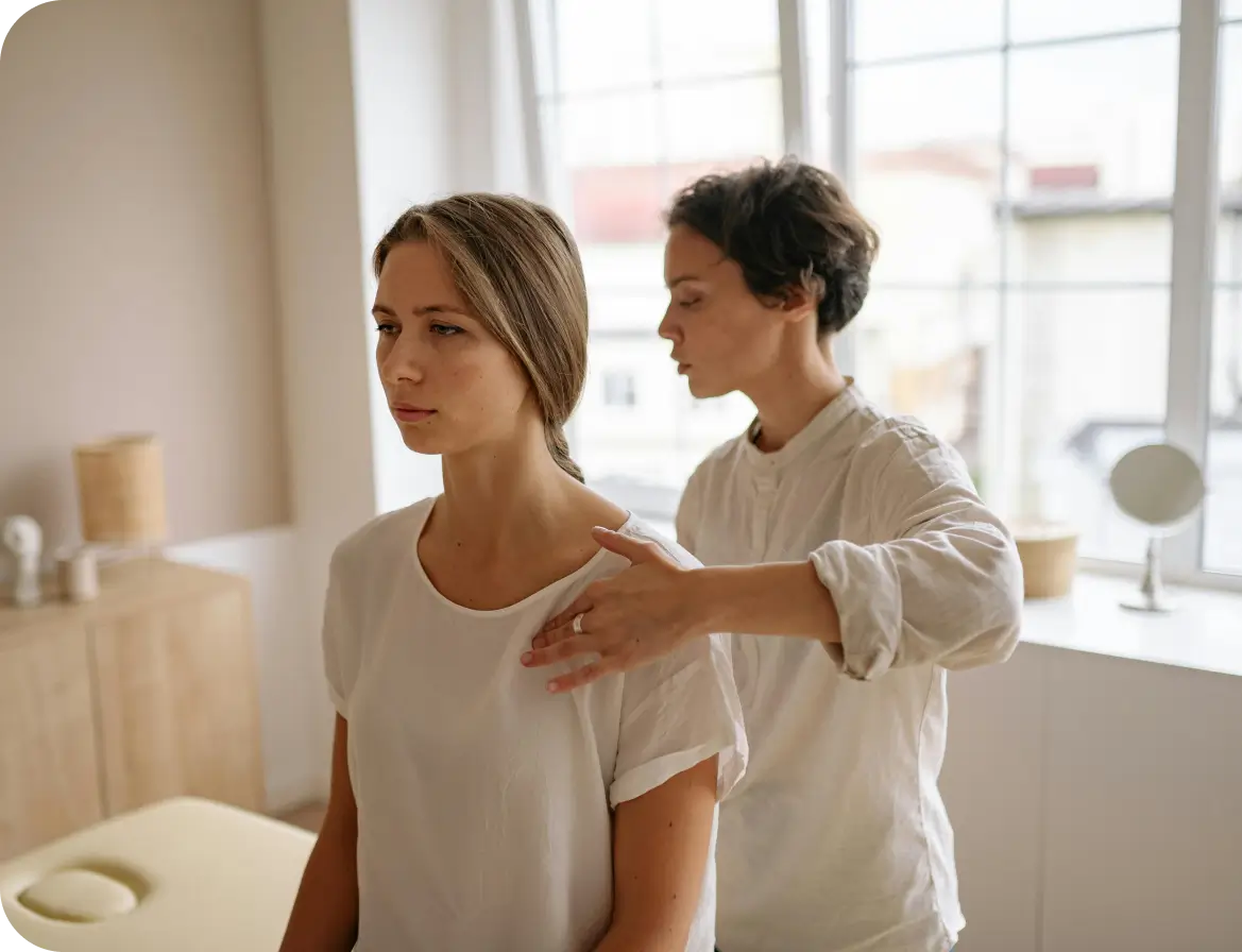Person receiving shoulder therapy in bright room.
